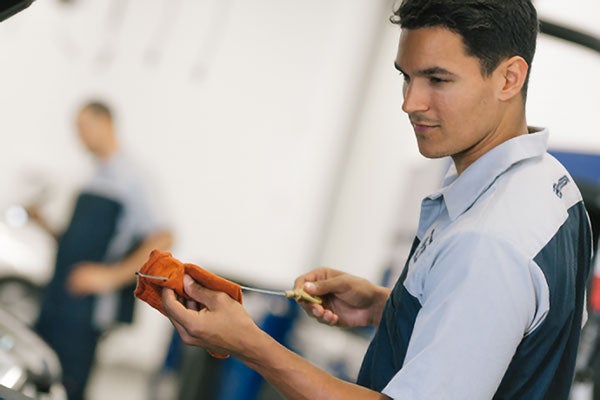 Mechanic checking oil level with a dipstick and wiping it with a cloth