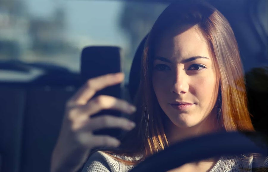 women sitting on driving and using cellphone
